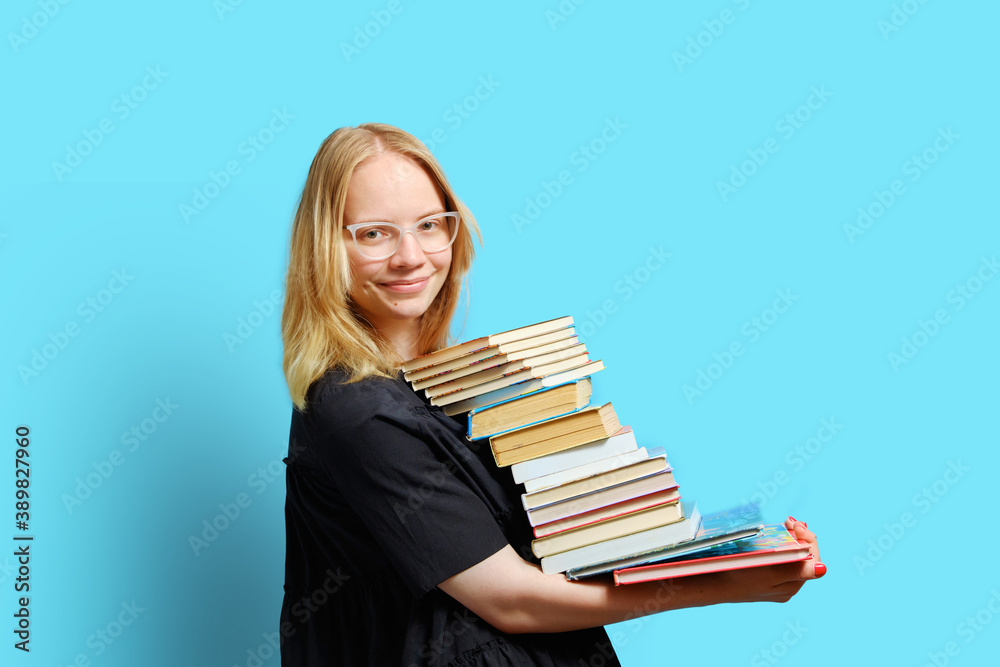 Studio half-length portrait of a joyful Caucasian student with a large stack of books in his hands.. Studio half-length portrait of a joyful Caucasian student with a large stack of books in his hands..