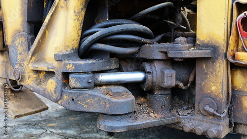 Cylinder and rod with old hydraulic hoses. Long-term use of heavy machinery causes the hydraulic system to deteriorate and dirty with old oil left on the equipment. Close focus and select an object