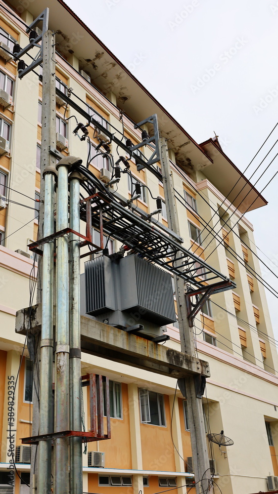 Power transformers and wires on the pole. Transformer with pipes and rafts for large buildings On the background of tall buildings and white skies. Close focus and select an object