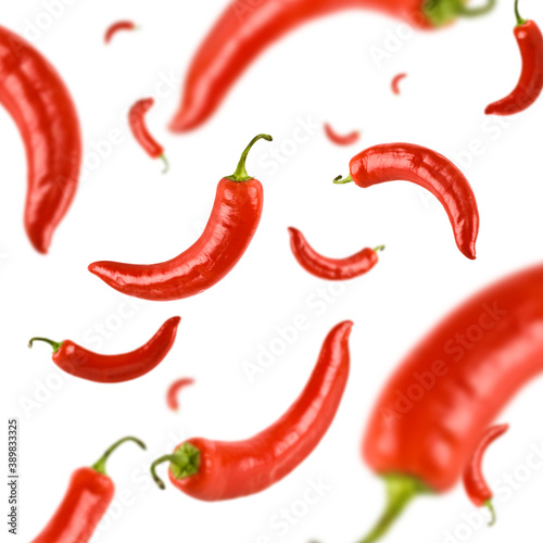 Many red chili peppers free falling on white background. Selective focus - shallow depth of field.
