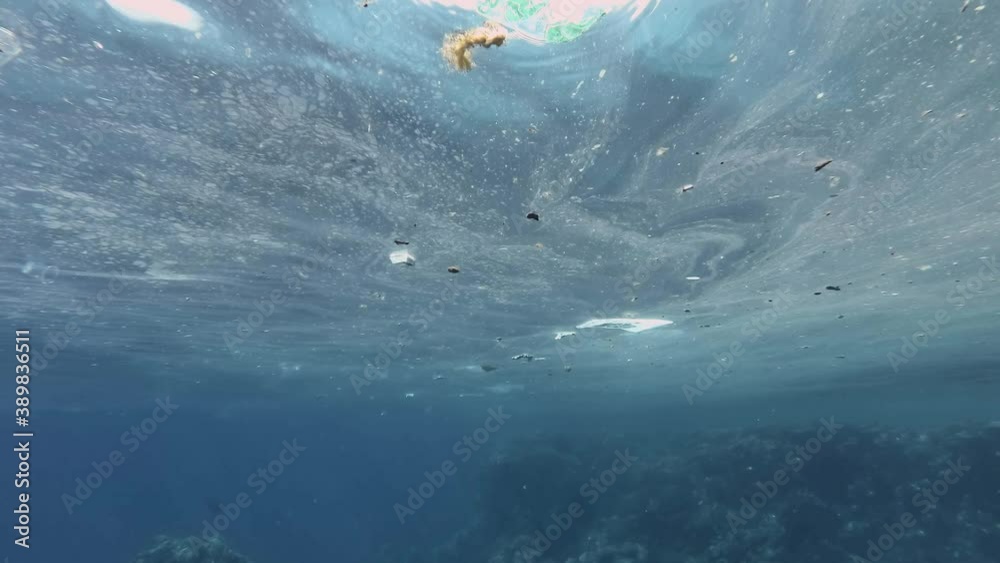 Plastic and other garbage slowly drifting on surface of the water approaching the coral reef. Massive polluting of the Ocean. Slow motion, Underwater shot Plastic and other garbage slowly drifting on surface of the water approaching the coral reef. Massive polluting of the Ocean. Slow motion, Underwater shot