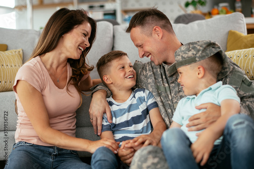Happy soldier sitting on the floor with his family. Soldier and his wife enjoying at home with children © JustLife