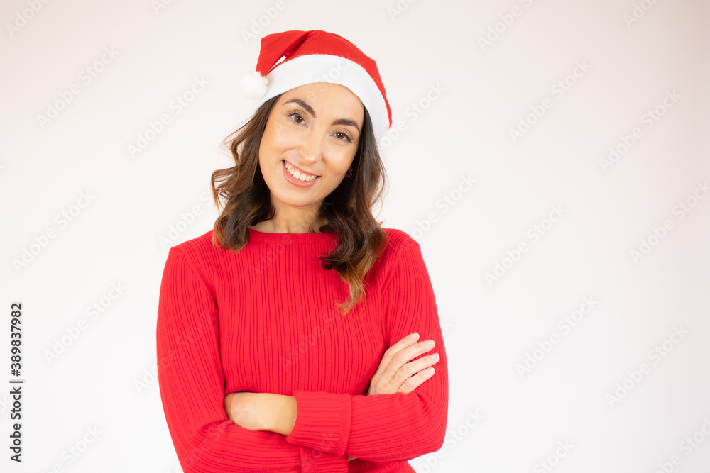 Portrait of a smiling young woman wearing red sweater and santa hat standing with arms folded isolated over white background