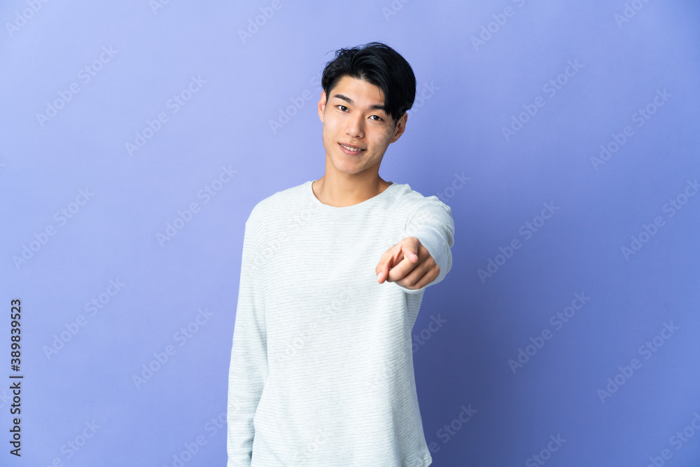 Young Chinese man isolated on purple background pointing front with happy expression Young Chinese man isolated on purple background pointing front with happy expression
