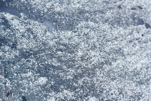 Melting snow on the car window. Close-up of ice crystals.