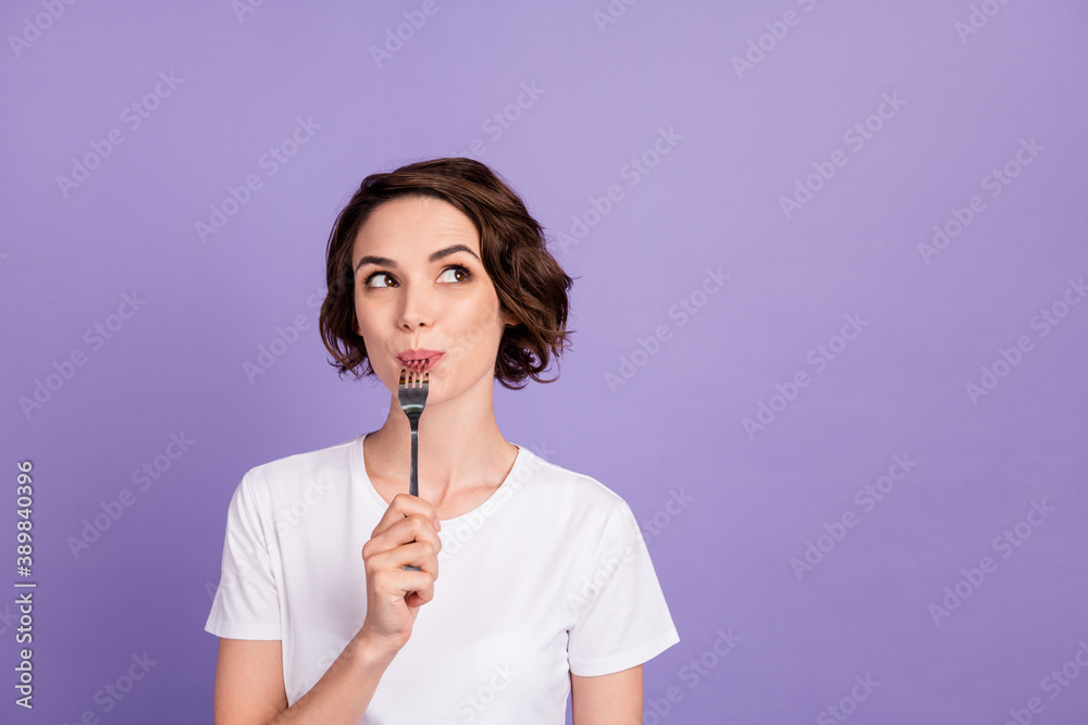 Portrait photo of dreamy girl licking fork thinking about diet looking at empty space isolated on bright purple color background Portrait photo of dreamy girl licking fork thinking about diet looking at empty space isolated on bright purple color background