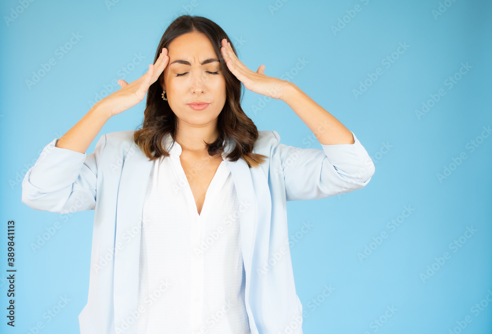 Stressed young woman calming down relieving headache emotional stress relief, nervous young woman meditating massaging temples doing breathing exercises isolated on blue background Stressed young woman calming down relieving headache emotional stress relief, nervous young woman meditating massaging temples doing breathing exercises isolated on blue background