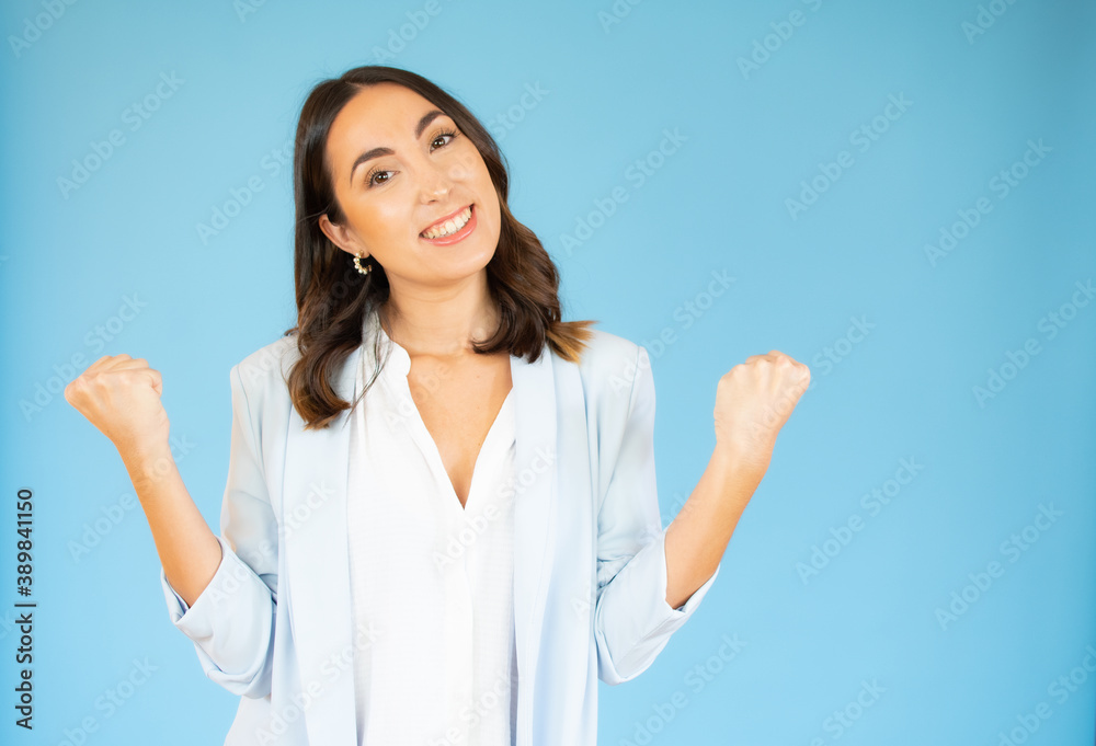 Photo of cheerful beautiful young woman standing isolated over blue background. Looking camera showing winner gesture. Photo of cheerful beautiful young woman standing isolated over blue background. Looking camera showing winner gesture.