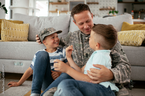 Happy soldier sitting on the floor with his family. Soldier enjoying at home with children.