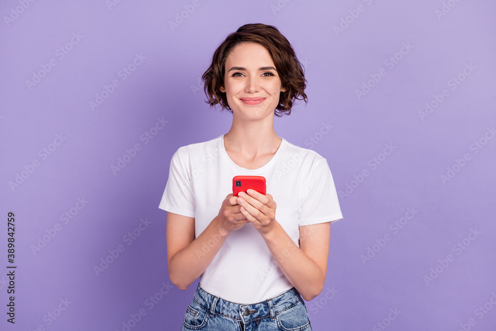 Photo portrait of cute female hipster keeping cellphone typing message smiling isolated on vivid violet color background Photo portrait of cute female hipster keeping cellphone typing message smiling isolated on vivid violet color background