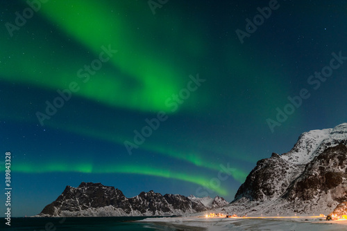 Spectacular dancing green strong northern lights over the famous round boulder beach near Uttakleiv on the Lofoten islands in Norway on clear winter night with snow-clad mountains © Robert Ruidl