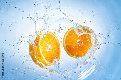 Two halves of orange fruit splashing into clear water.