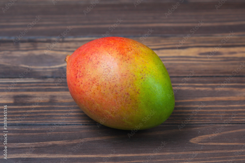 Ripe mango fruit, lies on a background of wooden boards Ripe mango fruit, lies on a background of wooden boards