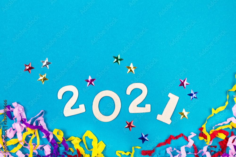 Año 2021, números en madera sobre un fondo azul liso y aislado junto a estrellas de colores y confeti. Vista superior. Copy space Año 2021, números en madera sobre un fondo azul liso y aislado junto a estrellas de colores y confeti. Vista superior. Copy space