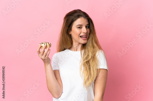 Young blonde woman isolated on pink background holding a donut