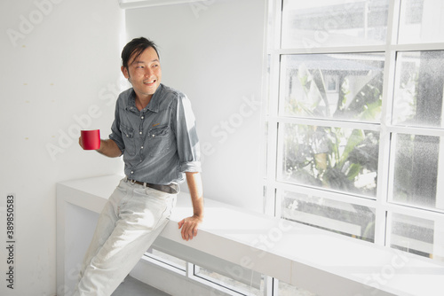 Man standing smile in the morning with red cup of coffee in his hand