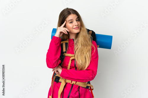 Young mountaineer woman with a big backpack over isolated background thinking an idea