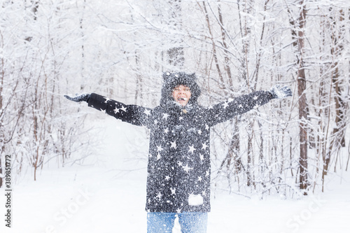 Happy young girl throw up a snow in a winter forest © satura_