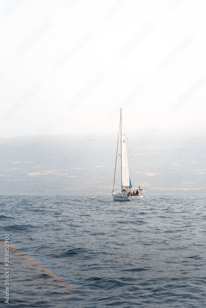 Obraz premium Small sailing boat sailing in the ocean near the coast of Tenerife