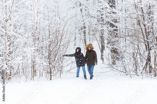 Young couple walking in a snowy park. Winter season.