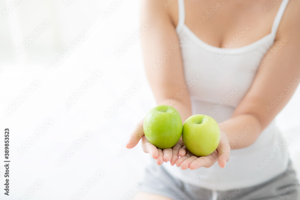 Closeup young asian woman holding and eating green apple fruit in the bedroom at home, lifestyle of nutrition girl healthy and care weight loss, health and wellness concept. Closeup young asian woman holding and eating green apple fruit in the bedroom at home, lifestyle of nutrition girl healthy and care weight loss, health and wellness concept.