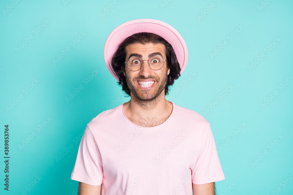 Photo portrait of crazy man grinning with white teeth wearing pink t-shirt hat glasses isolated on vivid teal color background