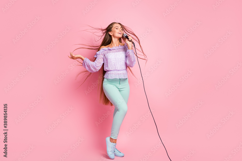 Full length photo of charming teen girl wear casual purple outfit singing microphone isolated pastel pink color background