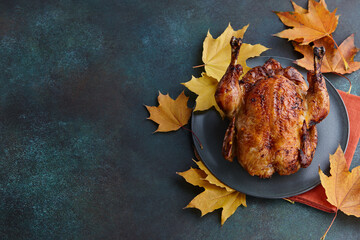 Roasted turkey or chicken dish decorated with autumn maple leaves for Thanksgiving dinner