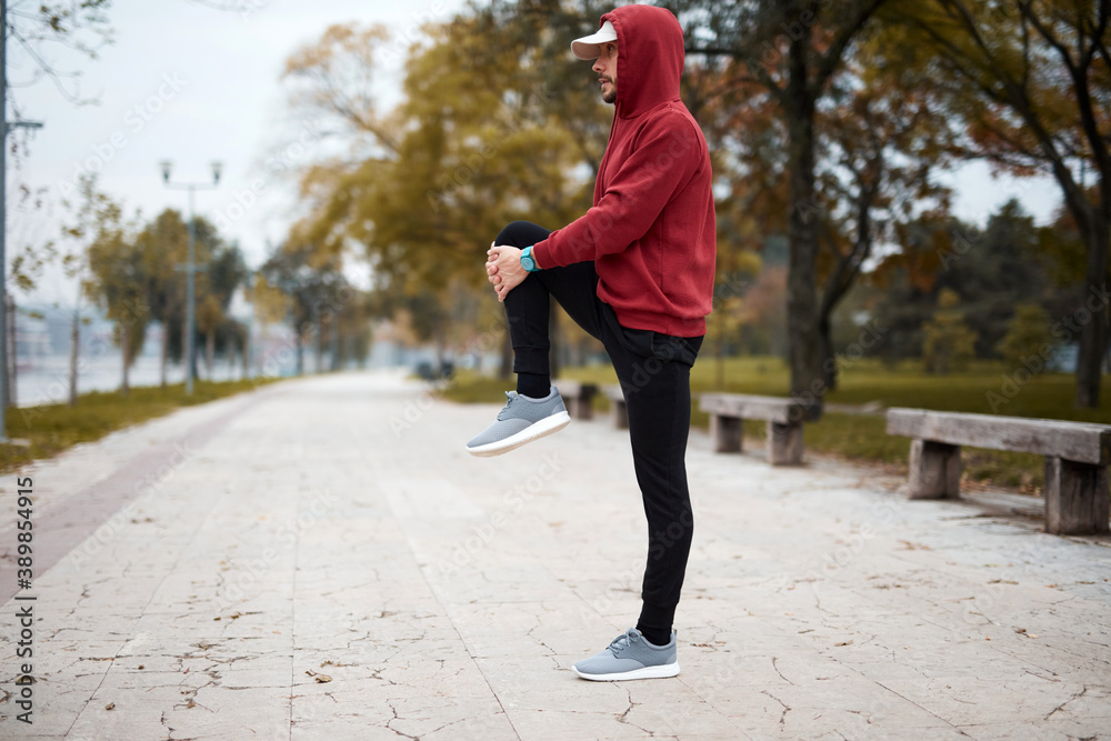 Fototapeta premium Athletic sporty man training in hoodie sweatshirt in urban city park.
