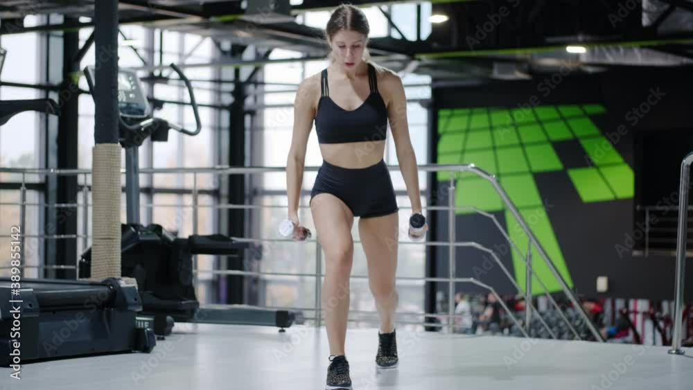 Fitness woman multifunctional workout in the gym. Sportswoman trains with dumbbells doing various exercises Fitness woman multifunctional workout in the gym. Sportswoman trains with dumbbells doing various exercises