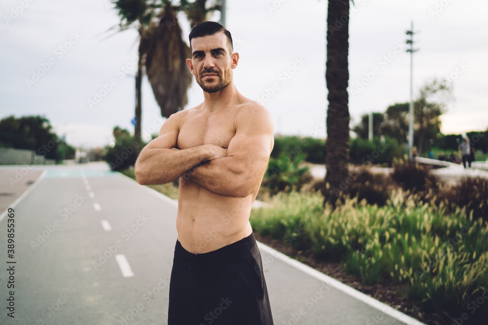 Shirtless ethnic athlete resting on road in park