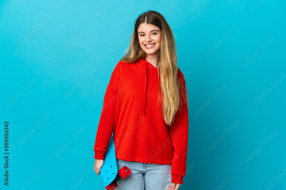 Young blonde woman isolated on blue background with a skate Young blonde woman isolated on blue background with a skate