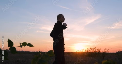 Silhouette of young male kung fu fighter practising alone in the fields during sunset 