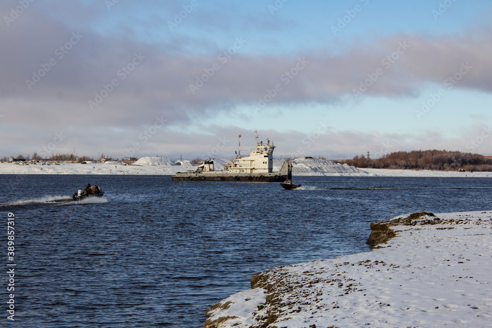 At the end of the navigation period. A tug on the Irtysh river is going to transport a barge with cargo. In late autumn, snow lies on the banks, the river is not frozen yet.