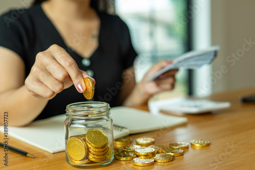 Woman taking note And make income and expenditure accounts by putting coins in the savings and counting cash To save money Keep it as retirement money, ideas for saving money for the future