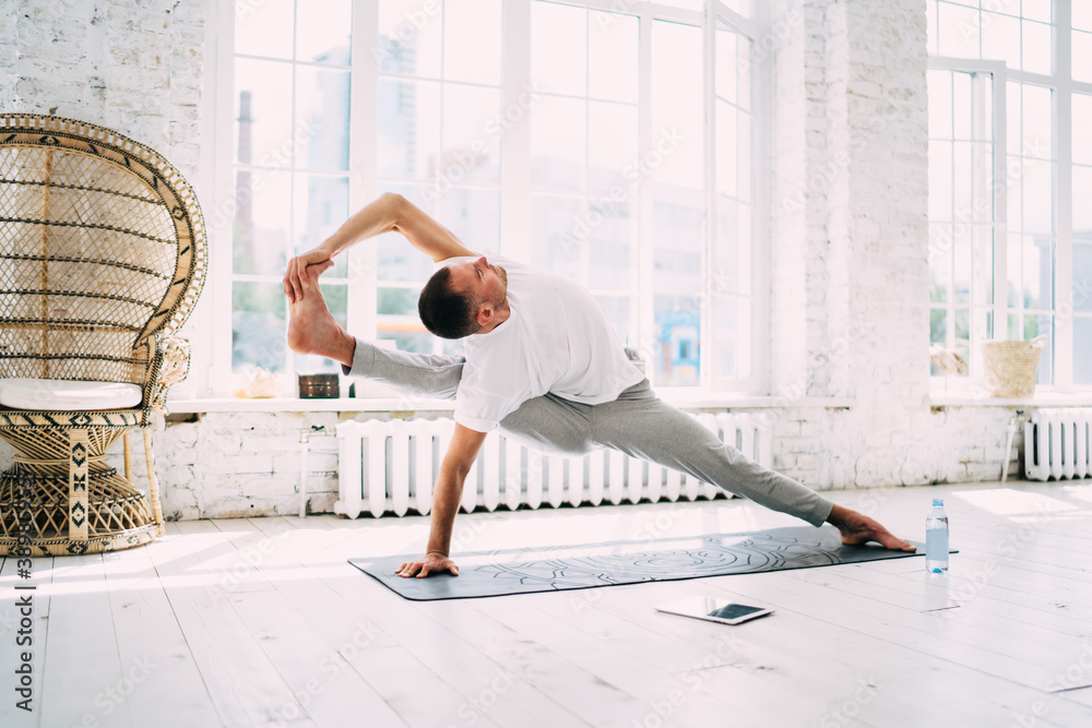 Flexible man standing in Visvamitra asana Flexible man standing in Visvamitra asana
