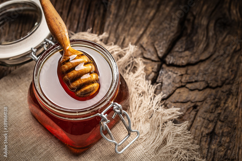 Jar of honey with dipper on wooden table - closeup