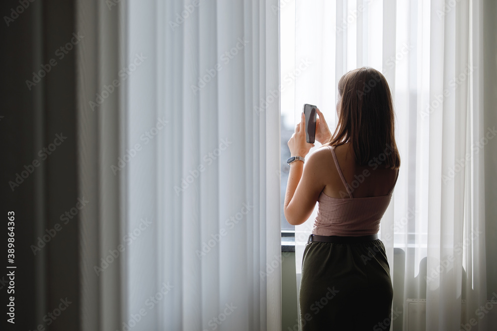 Woman with smartphone at the window Woman with smartphone at the window