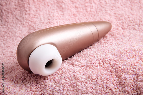 Clitoral suction and stimulator. Contactless satisfyer sex toy for women. Silicone and plastic vibrator. woman masturbation device over pink towel background