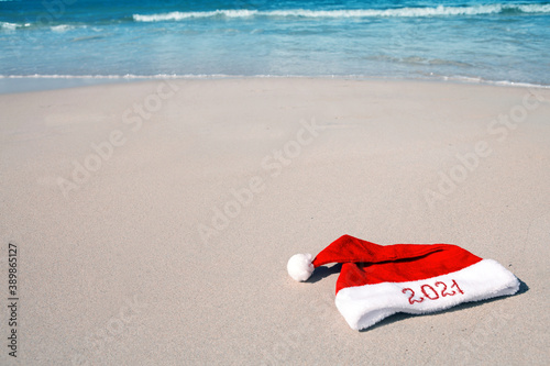 Year 2021 written at the Santa Claus hat on caribbean beach.