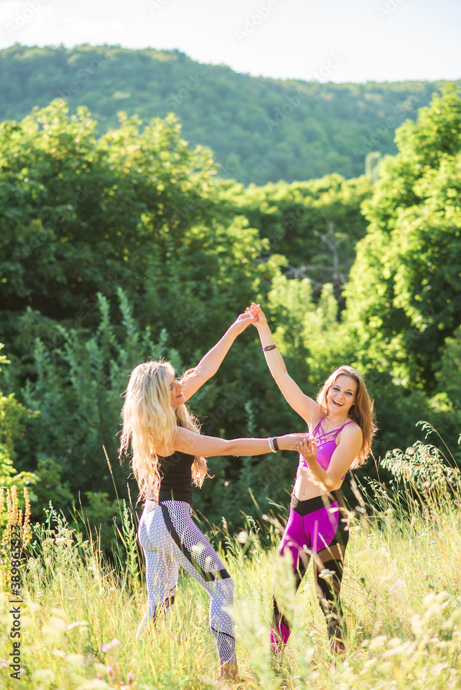 Fototapeta premium Woman yoga instructor teaching beginner in nature on a sunny day