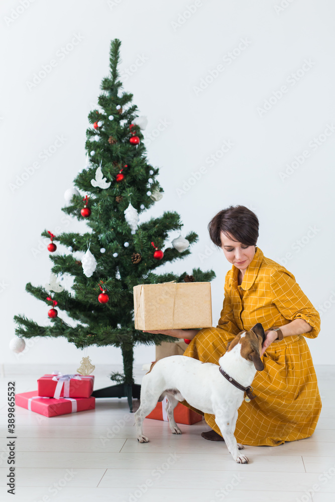 Happy young woman with lovely dog opening present box under christmas tree. Holidays concept. Happy young woman with lovely dog opening present box under christmas tree. Holidays concept.