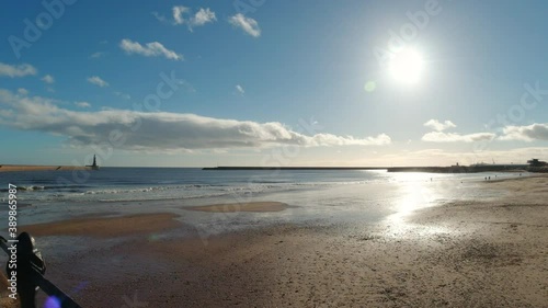 4k Video taken from Roker Pier looking out to Roker Beach on a beautiful sunny day with silhouettes of people walking their dogs enjoying the sunshine at Sunderland, Tyne and Wear.