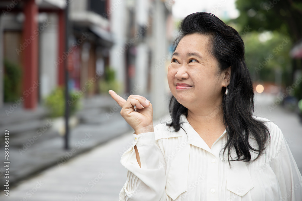 Happy smiling old Asian Chinese senior woman pointing up
