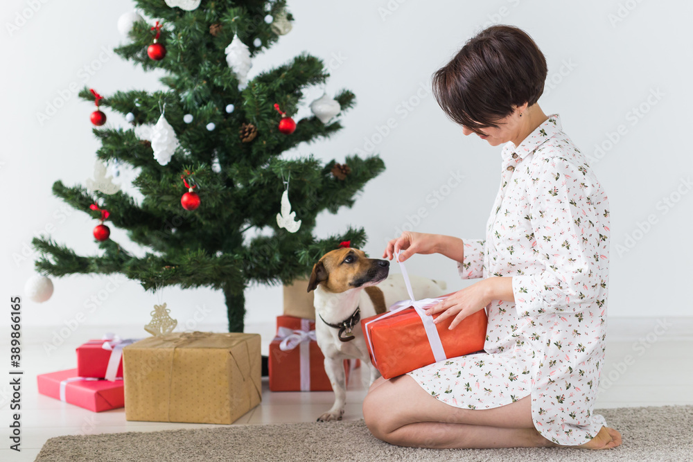 Happy young woman with lovely dog opening present box under christmas tree. Holidays concept. Happy young woman with lovely dog opening present box under christmas tree. Holidays concept.