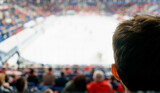 Silhouette male fans in the stands while watching a hockey game.