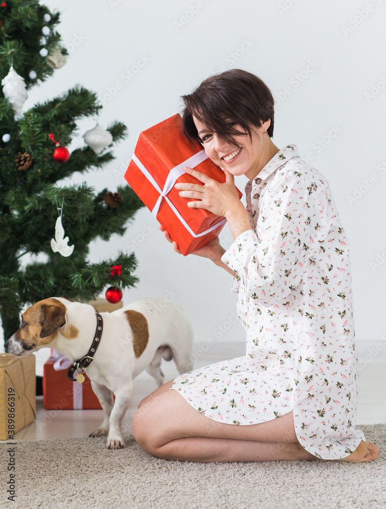 Happy young woman with lovely dog opening present box under christmas tree. Holidays concept. Happy young woman with lovely dog opening present box under christmas tree. Holidays concept.