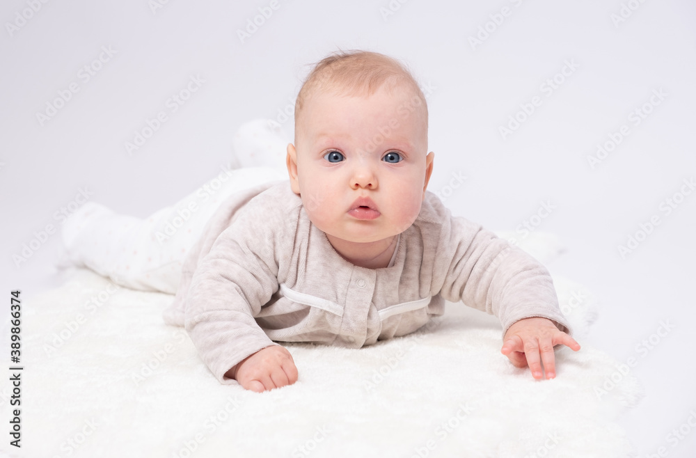 Pretty baby plays on the floor with a toy, white background