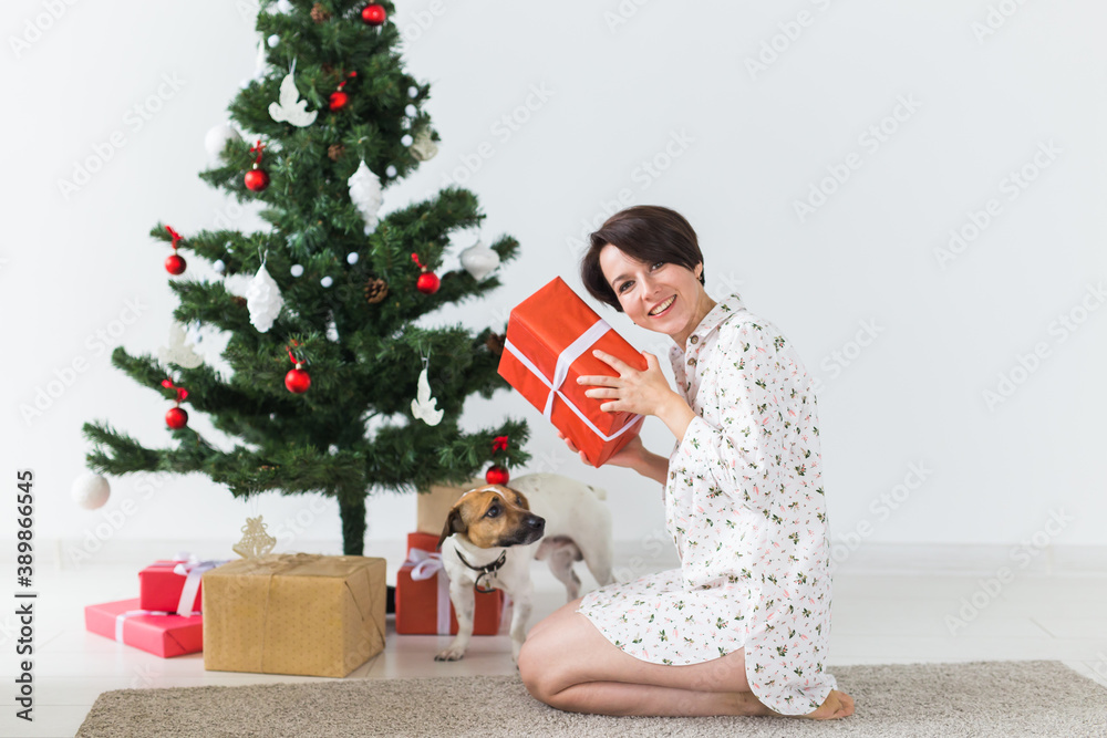 Happy young woman with lovely dog opening present box under christmas tree. Holidays concept. Happy young woman with lovely dog opening present box under christmas tree. Holidays concept.