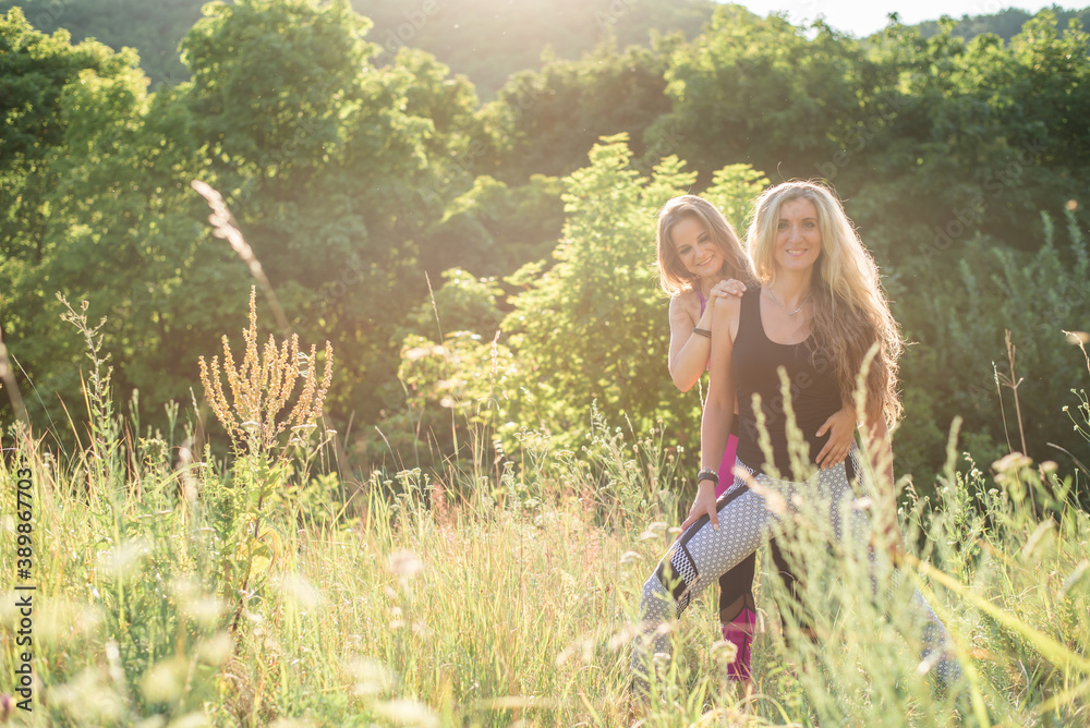 Woman yoga instructor teaching beginner in nature on a sunny day